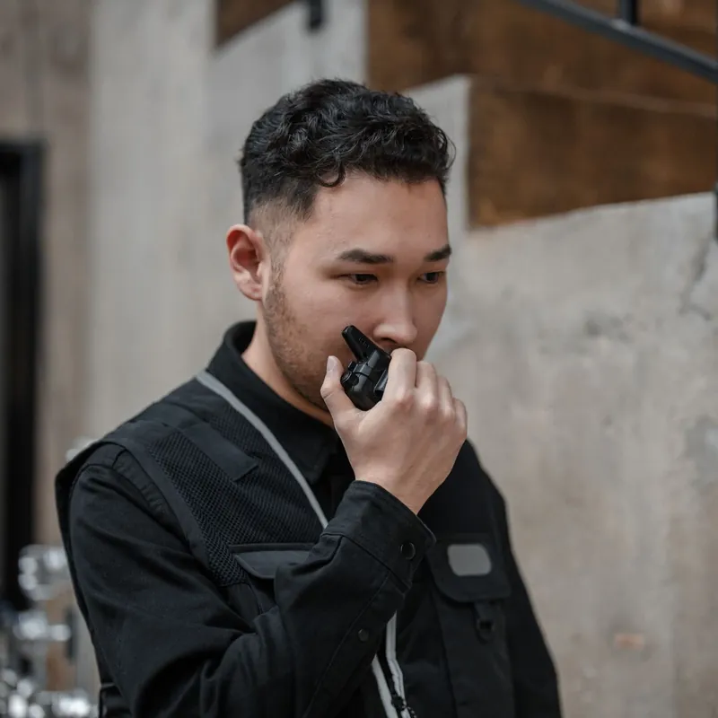 Vigilante de seguridad vestido de oscuro hablando por un walkie-talkie