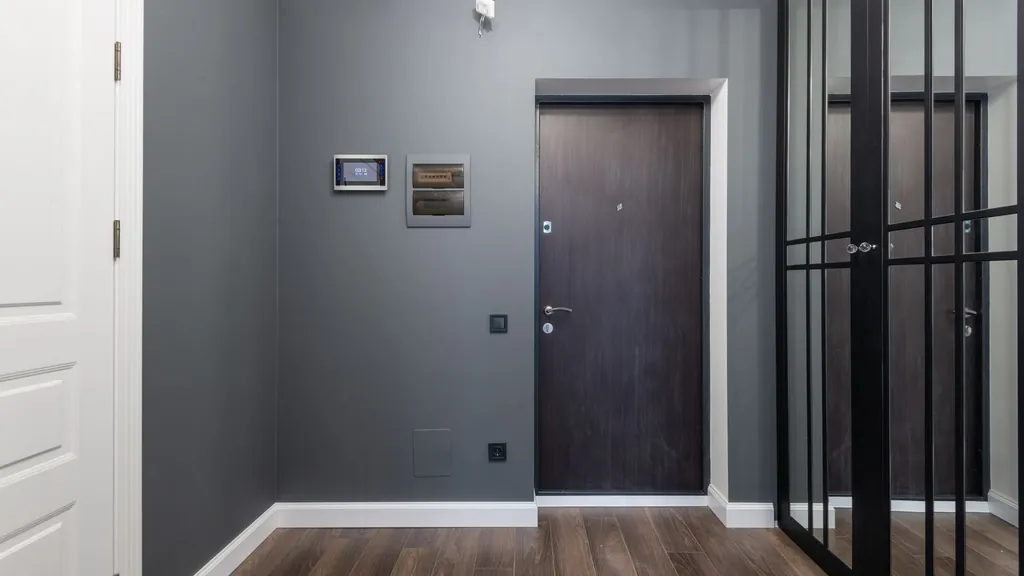 Recibidor de un piso con un panel de control en la pared junto a la puerta de entrada