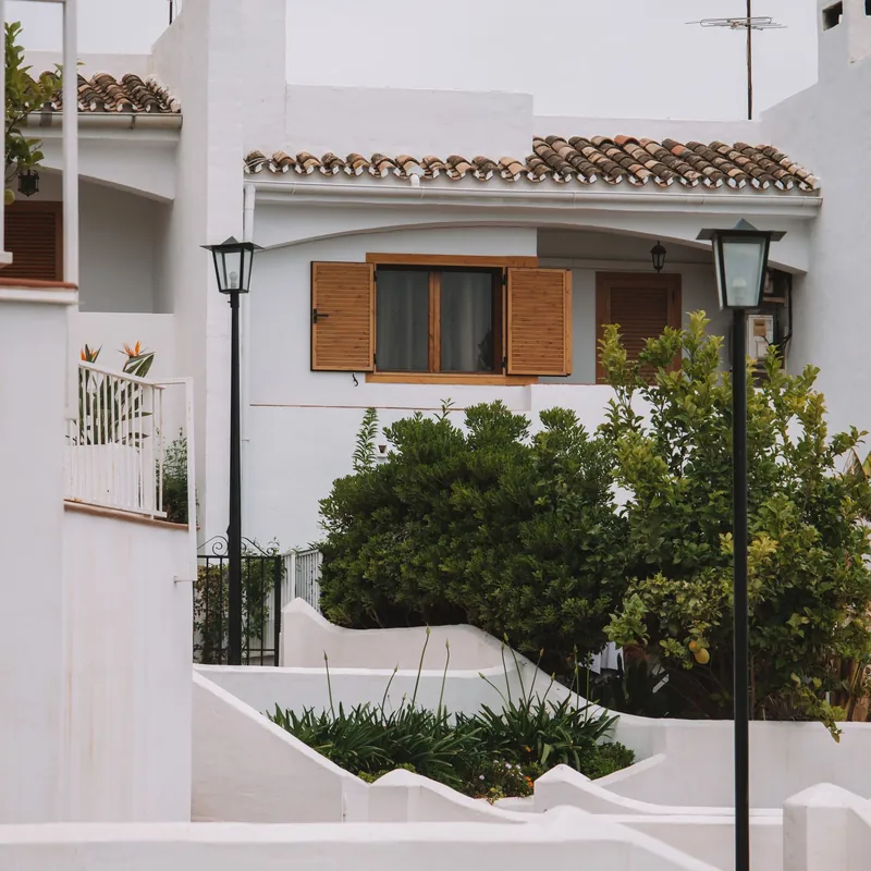 Casa blanca con contraventanas de madera y jardín en una urbanización de Málaga
