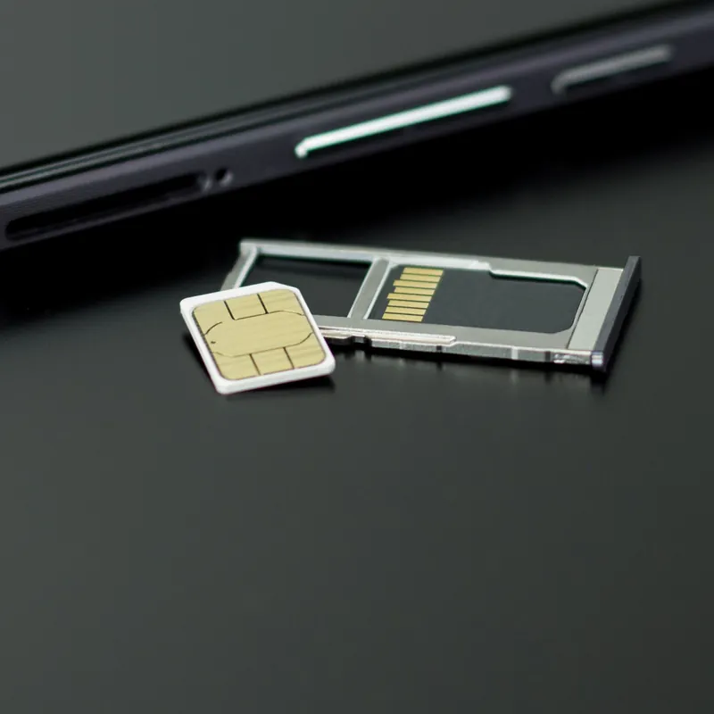 Tarjeta SIM y bandeja extraída junto a un teléfono móvil negro